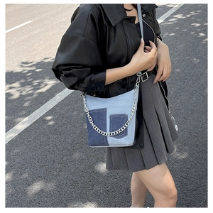 Fashionable blue denim patchwork crossbody bag with silver metal chain on casual model