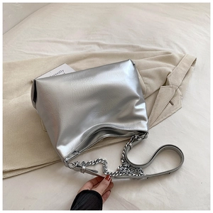 Macro detail of silver metallic leather texture and chunky chain strap on shoulder bag