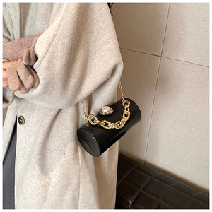 Chic black acrylic cylinder evening bag with large pearl clasp and gold chain detail