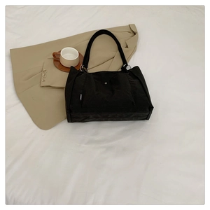 Close-up of minimalist black nylon tote bag with white woven label and metal rings