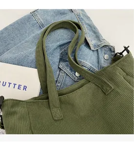 Detailed close-up of dark green corduroy tote bag texture with sturdy dual handles