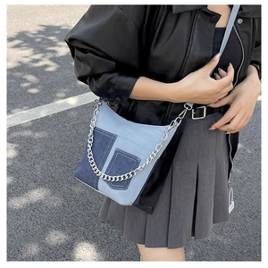 Detail of denim patchwork bucket bag with silver chain strap on model in outdoor light