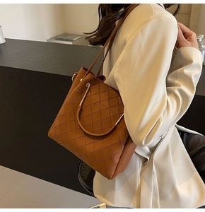 Detail of brown quilted bucket bag with golden metal ring handle and leather straps