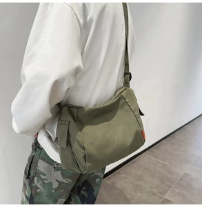 Détail du sac messager en toile vert armée avec poche latérale et bandoulière réglable