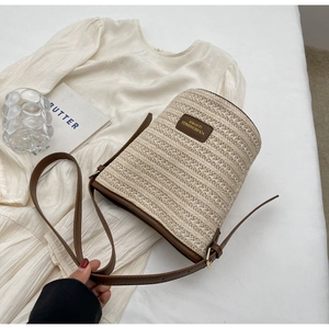Detail of woven straw and brown leather stitching on bucket bag with logo tag
