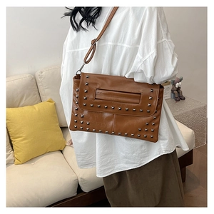 Macro di una borsa a busta vintage in pelle marrone con rivetti quadrati e fessura per manico