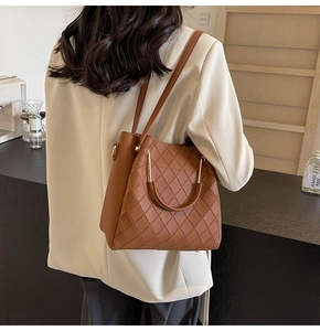 Detailed view of caramel brown leather bucket bag with quilted stitching and gold hardware