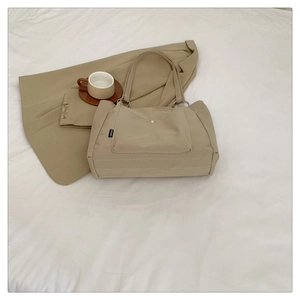 Detail of khaki canvas tote bag with metal snap pocket and rings on white fabric