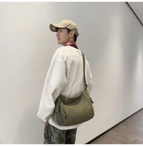 Détail de la sacoche en toile vert olive montrant la poche latérale et la sangle