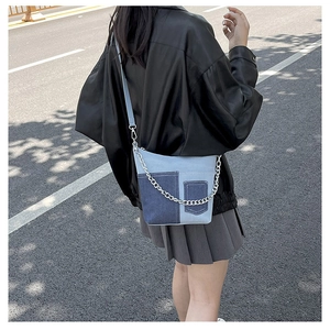 Detail of patchwork denim crossbody bag with decorative pocket and silver metal chain