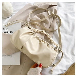 Détail du sac nuage beige plissé avec chaîne blanche épaisse et texture cuir souple