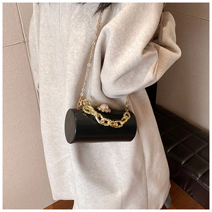 Detailed close-up of a black acrylic cylinder bag with gold chain and pearl buckle