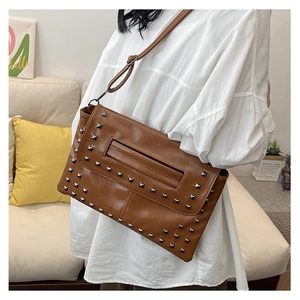 Dettaglio borsa in pelle marrone con borchie quadrate argentate e design con manico traforato