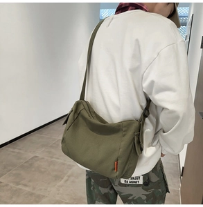 Détail du sac à bandoulière en toile vert olive avec étiquette orange décorative