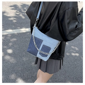 Detailed view of patchwork denim shoulder bag with metal chain and decorative pocket