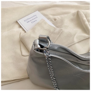 Detail of silver metallic hobo bag featuring crinkled leather and thick chain strap