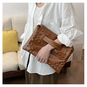 Dettaglio di una pochette in pelle lucida testa di moro con borchie argentate e cinturino