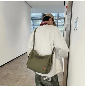Sac bandoulière en toile vert olive porté par un mannequin dans un intérieur épuré