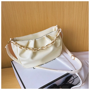 Close-up of cream white crescent bag with ruched texture and gold resin chain strap