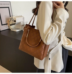 Detail of dark brown quilted leather bucket bag with large capacity and stylish weave design