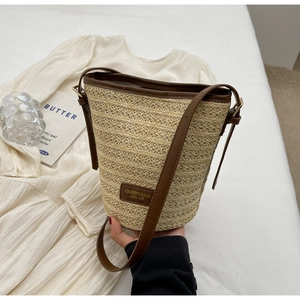 Detail showing the woven straw texture and leather brand patch of the bucket bag