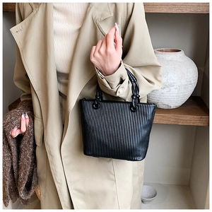 Detail view of black pleated bucket bag with unique round ring handle for casual styling