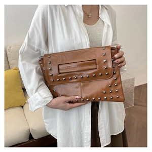 Dettaglio pochette in pelle caramello con borchie argento e fessura per impugnatura