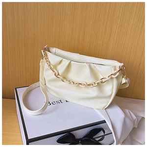 Detail of creamy white pleated cloud bag with metallic acrylic chain on display box