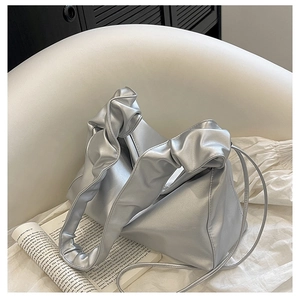 Silver pleated handle baguette bag with sleek geometric design on white soft seat