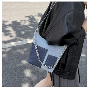 Detail of denim patchwork shoulder bag with silver chain and leather strap on model