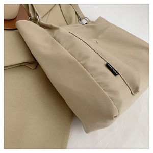 Detailed close-up of a khaki canvas tote bag with side pocket and metallic strap ring