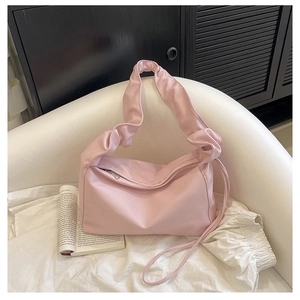 Detail of pink pleated cloud bag in satin nylon material on a modern white sofa