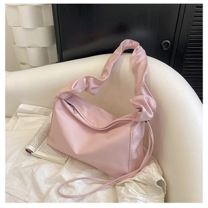 Detail view of pink ruched shoulder bag with cloud strap on a stylish sofa
