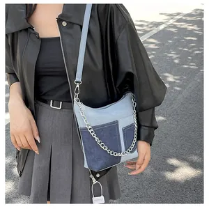 Detail of blue denim patchwork crossbody bag with silver chain and dual straps