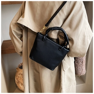 Detailed texture of black pleated leather bucket bag with gold hardware and shoulder strap