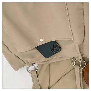 Close-up of beige tote bag showing pocket with metal snap button and strap ring