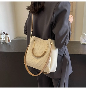 Detail view of woven leather bucket bag with gold hardware and brown shoulder strap