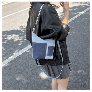 Detail of color-block denim crossbody bag with side pockets and silver chain strap