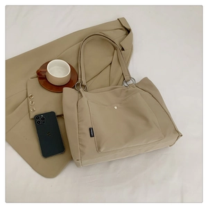 Close-up of khaki tote bag featuring front pocket with metal snap and logo detail