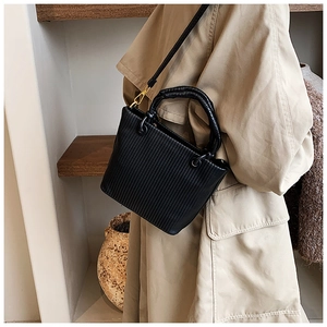 Vertical pleated bucket bag in black matte PU leather styled with a camel trench coat