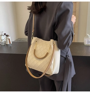 Detail of cream leather bucket bag showing diamond lattice texture and brown ring handle