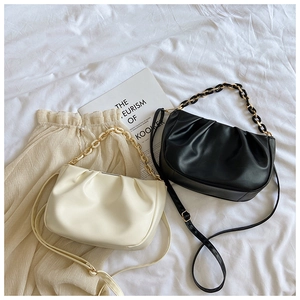 Detail of cream and black ruched cloud bags with chunky resin chains and soft leather