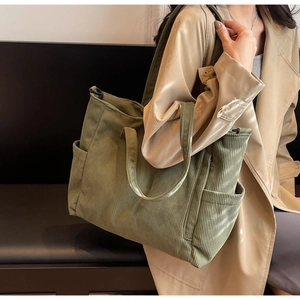 Detail of green corduroy tote bag showing textured vertical stripes and side pocket