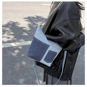 Detail of blue denim patchwork crossbody bag with chain strap on a model outfit