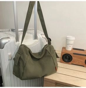 Détail du sac bandoulière en toile vert armée montrant la poche latérale et la sangle