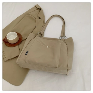 Detail of minimalist beige canvas tote bag with metal buckle pocket and shoulder straps
