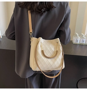 Detail of cream quilted bucket bag with contrast brown handle and gold hardware detail
