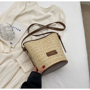 Macro shot of hand-woven straw bucket bag texture with brown leather strap detail