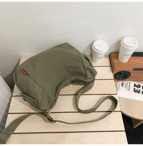 Détail du sac croissant en toile vert foncé avec bandoulière réglable et poche latérale