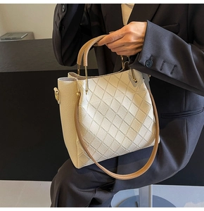 Detailed close-up of quilted beige bucket bag featuring gold metal hardware and leather texture